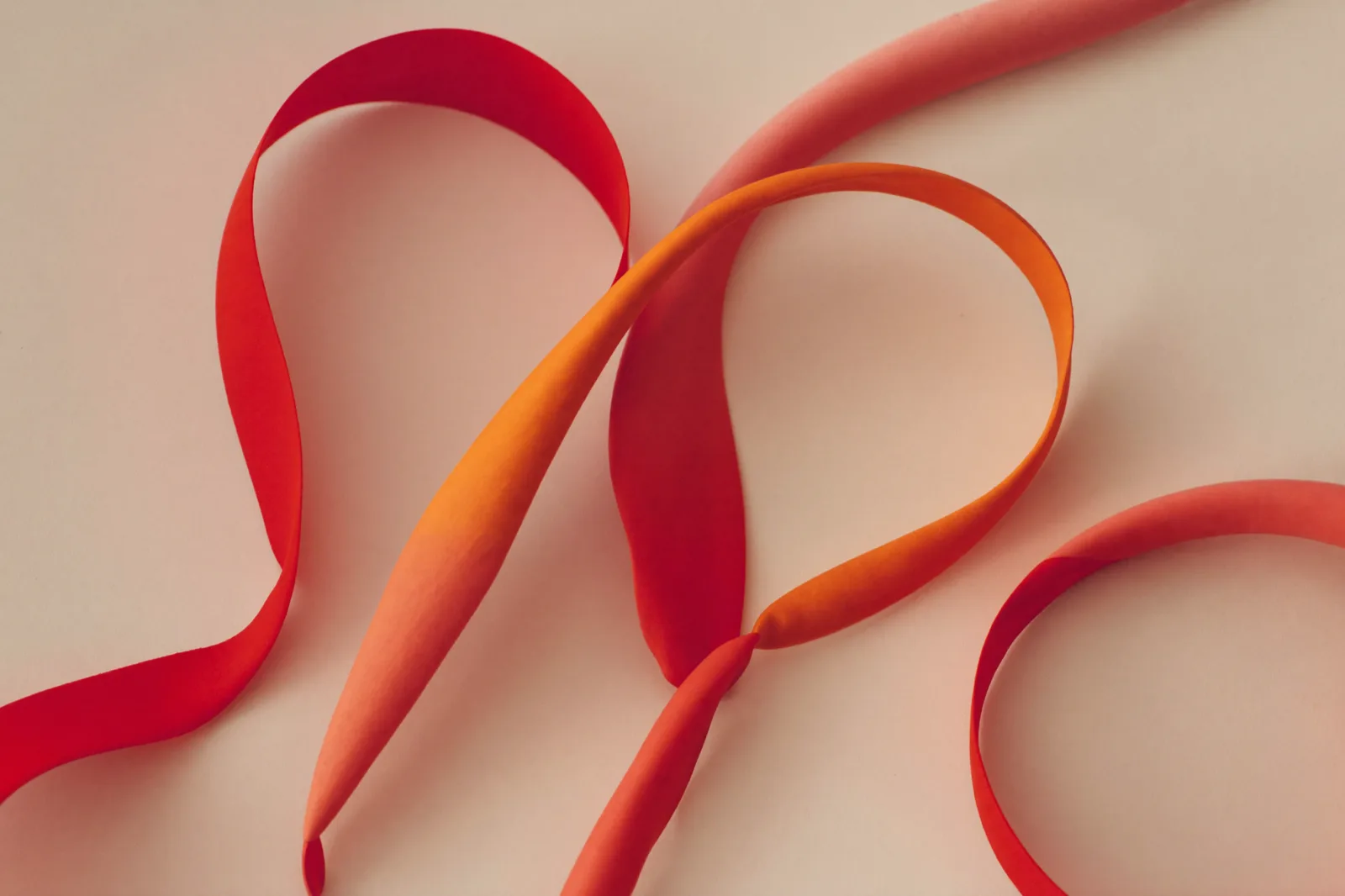 Abstract red-orange ribbon shapes echoing the Konzept brand mark on a warm cream background